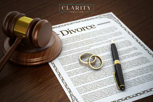 divorce forms, wedding rings, a pen, and a gavel on a table