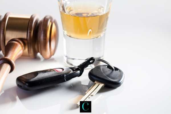 a gavel, glass of alcohol, and car keys on a white table