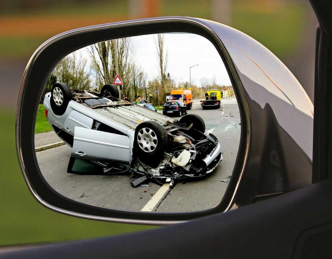  Overturned car wreck seen in a side-view mirror.