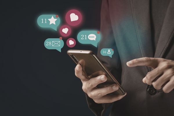 A person holding a phone with floating social media icons