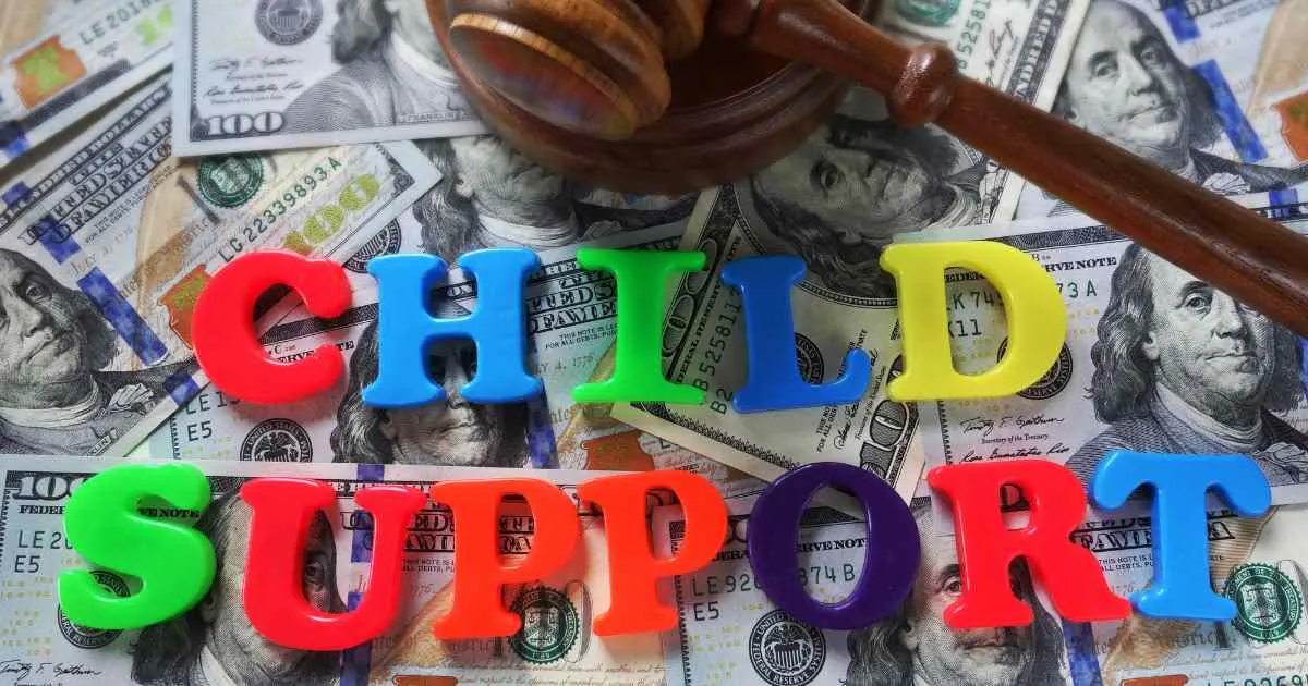 The words "CHILD SUPPORT" are spelled out in colorful letters on a bed of US hundred-dollar bills, with a gavel nearby.