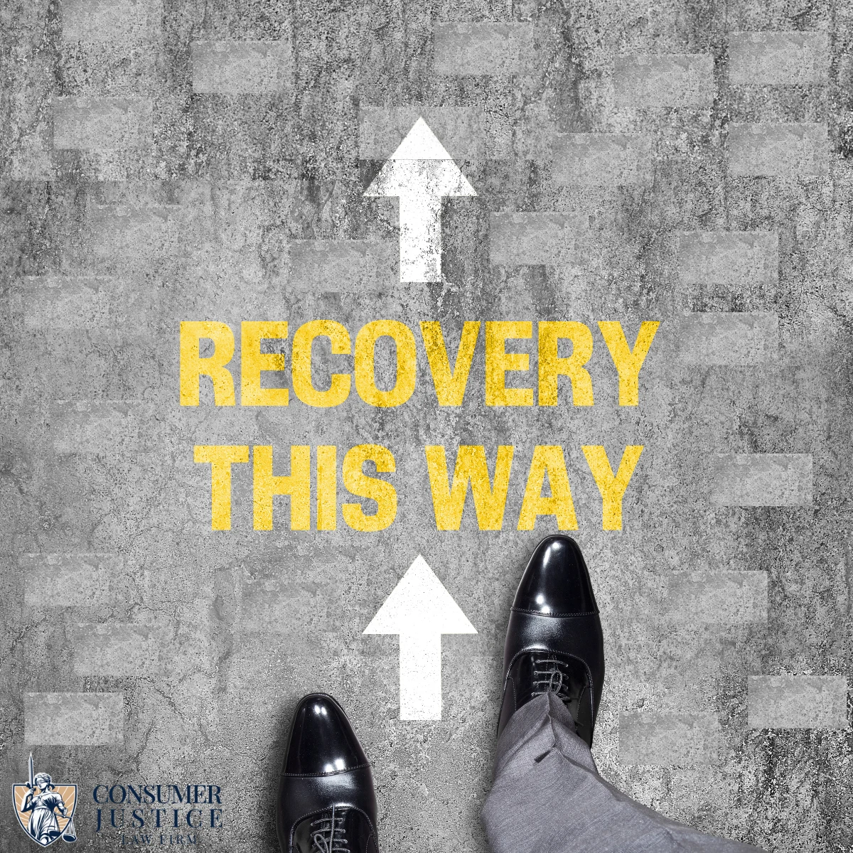 The feet of a man wearing black dress shoes and gray suit pants are shown stepping along a street from the perspective of him looking down at his feet. Two arrows on the ground point forward and the words "Recovery this way" appears. The image suggests that recovery is possible and that working with a lawyer for identity theft at Consumer Justice Law Firm is the path to achieve it.