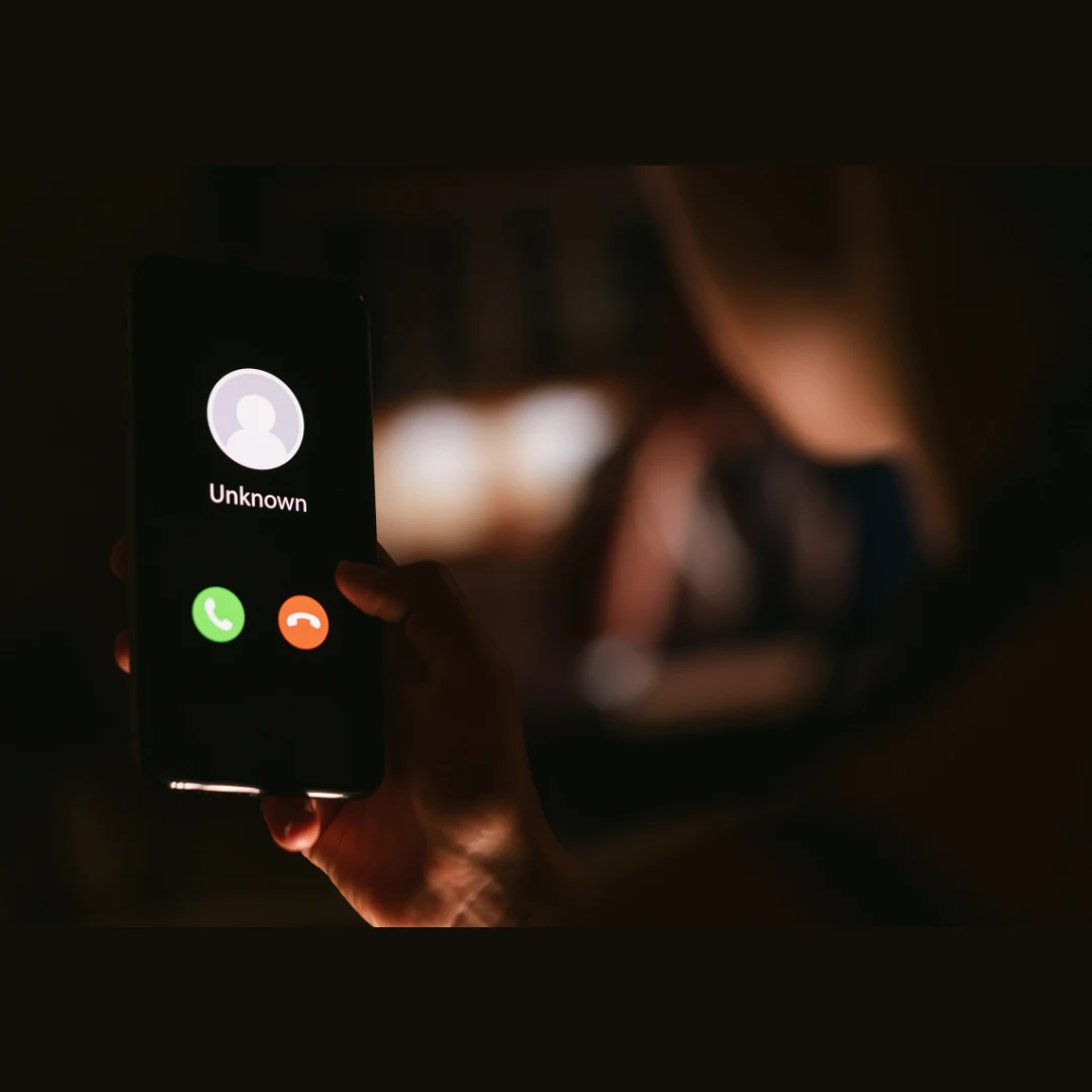 A phone screen in a dark room shows that a call is incoming. It conveys the intensity that a debt collector harassment attorney helps alleviate.