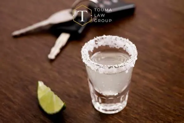 a shot of tequila and car keys on a bar