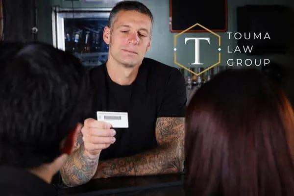 bartender checking the IDs of two customers