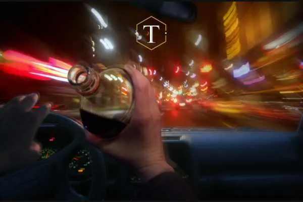 Man drinking from bottle of alcohol while driving