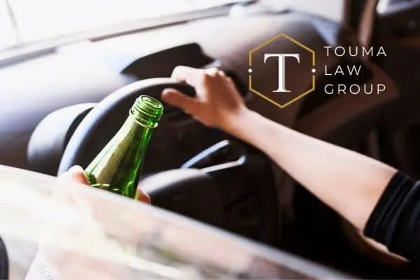 person behind the wheel holding a beer