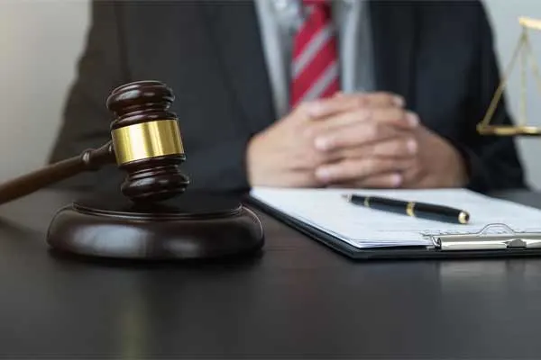 lawyer in suit sitting at desk with papers, a pen, and a gavel
