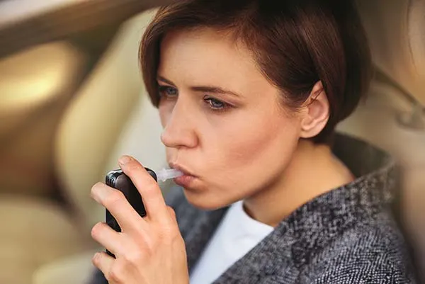 mujer soplando en un alcoholímetro