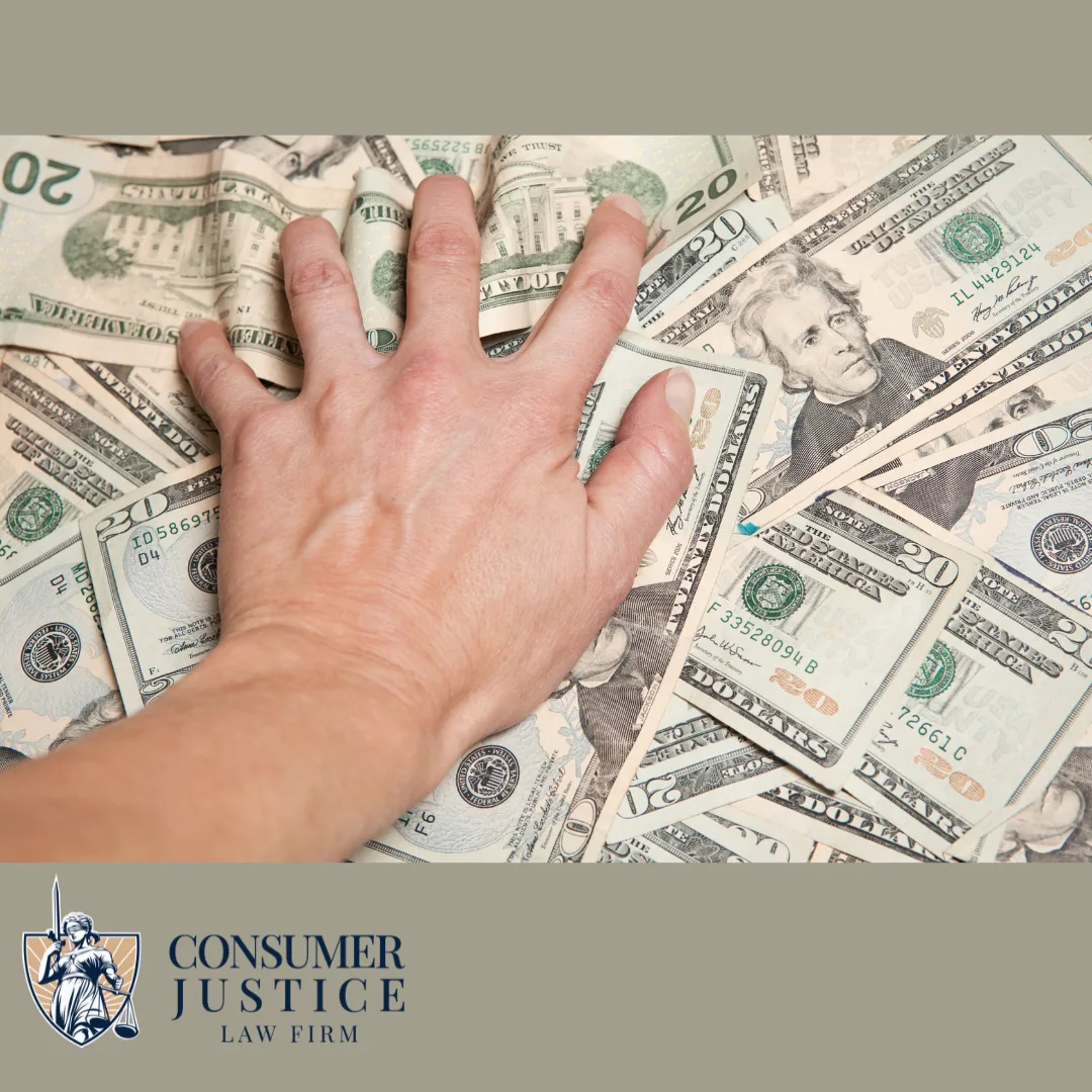 A hand grabs cash from a pile of money on a desktop. The image conveys how an unpaid overtime lawyer helps prevent wage theft.