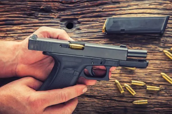 person loading a handgun with gold bullets on a plank of wood