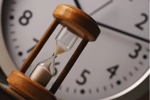Hour glass with a clock in the background
