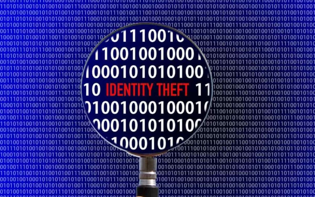 A magnifying glass over a background of binary code, highlighting the words "IDENTITY THEFT"