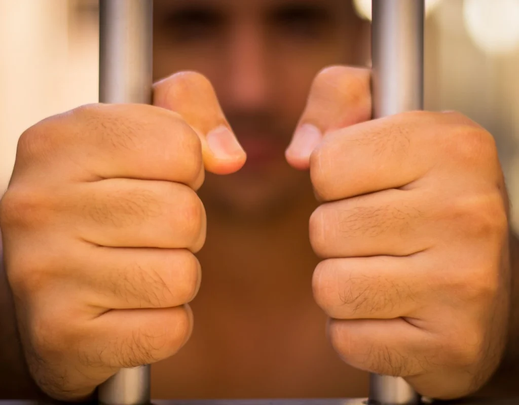 man behind jail bars holding them