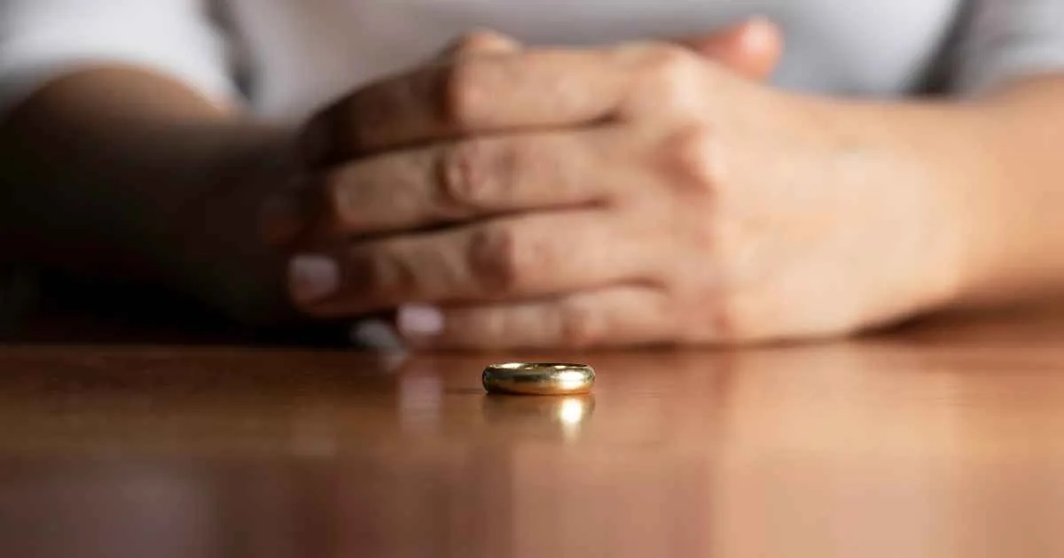 image of hands folded with a wedding ring resting in front