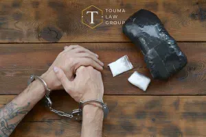a handcuffed man sitting next to a package of drugs