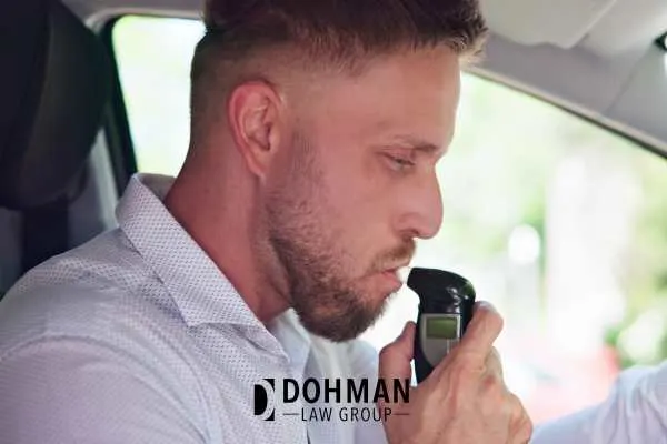 a man blowing into a baiid to start his car