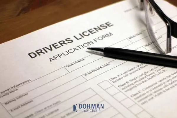 a drivers license application, glasses, and a pen on a desk
