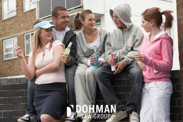 Underage boys and girls drinking alcohol outside.