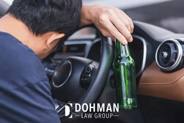 A man in a car with a beer bottle receiving a DUI and possible Illinois driver’s license suspension and revocation.