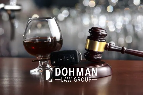 a glass of alcohol next to a gavel with a car key sitting on it