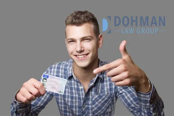 a man pointing at his newly acquired driver's license