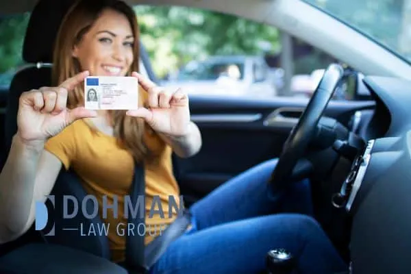 a woman sitting in her car showcasing her new license