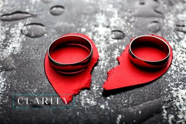 a torn paper heart with two wedding rings on top of it