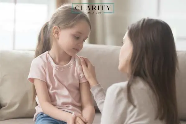 Mother kneeling in front of daughter with her hand on her shoulder