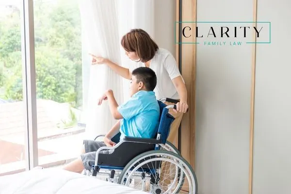 A woman pointing out a window to a boy in a wheelchair,