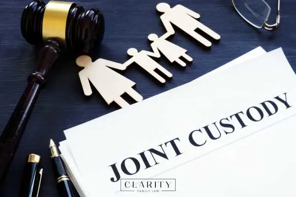 joint custody forms, a gavel, and cutout of a family on a desk