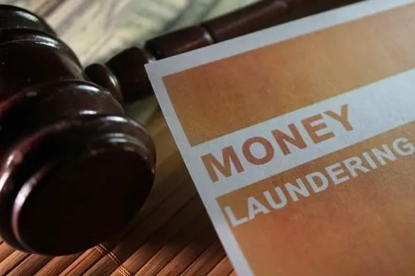 a gavel, money, and form covering the money laundering legal statute on a desk