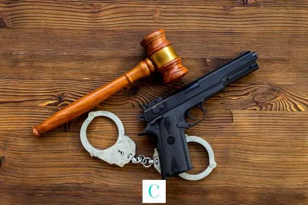 a pistol, gavel, and handcuffs on a wooden table