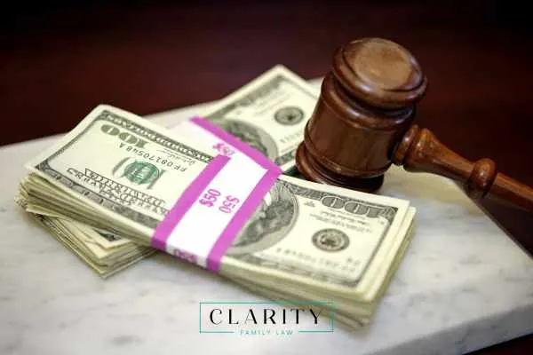 Stacks of $100 bills and a wooden gavel resting on a white marble surface.