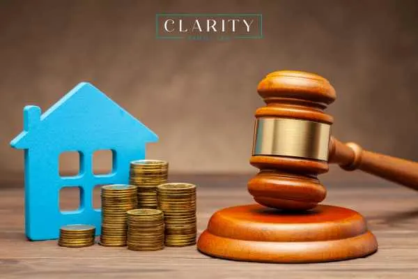 money, a model of a home, and a gavel on a desk