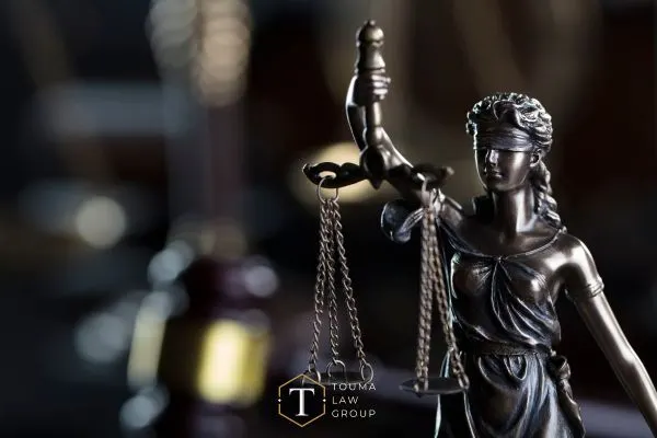 a desk with a books covering legal statutes, a gavel, and statue of justice on it