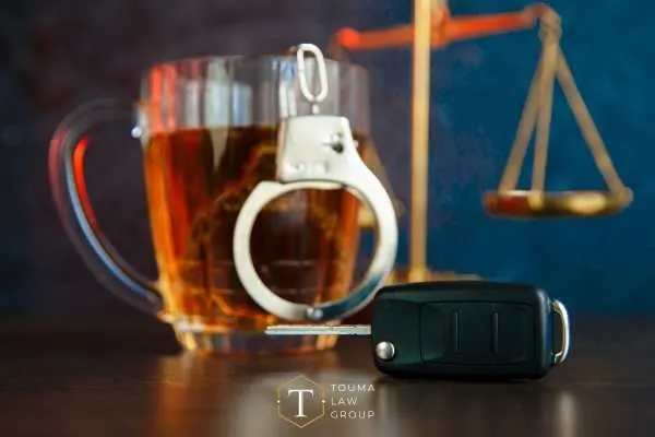 a beer, car key, gavel, and scales on a desk