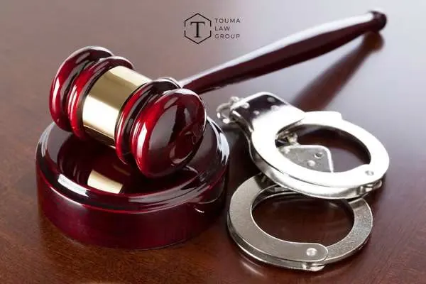 A judge's gavel and a pair of handcuffs resting on a wooden table.
