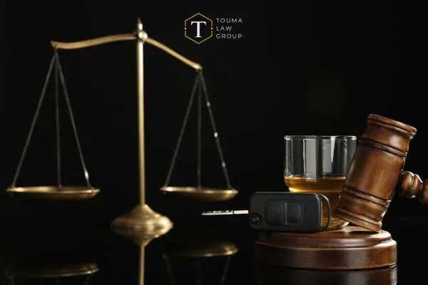 alcohol, a gavel, and scales of justice in front of a black background