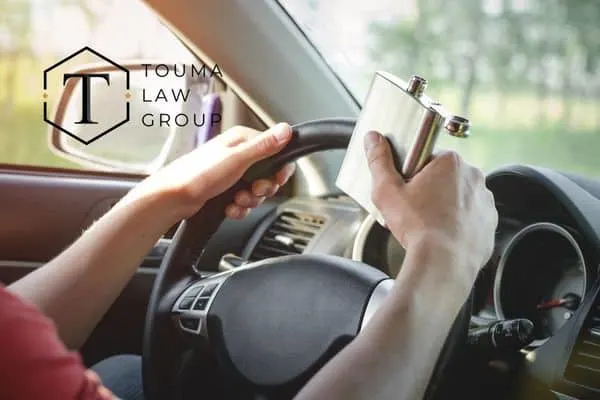a person drinking out of a flask while behind the wheel of their car