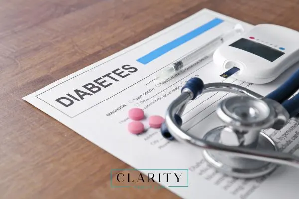 Close-up of a diabetes diagnosis document on a wooden table, surrounded by a syringe, glucose meter, pink pills, and a stethoscope.