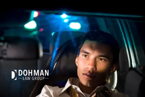 Man in car at night, with blue flashing lights (police lights) reflecting on him.