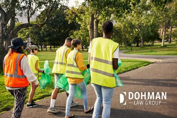 People in bright vests picking up trash in a park.
