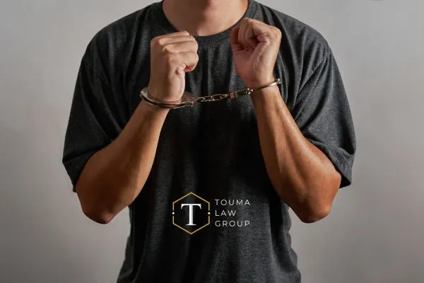 man in gray t-shirt holding up his hands that are handcuffed
