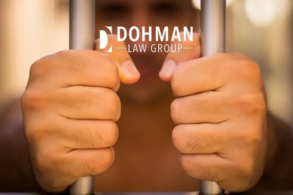 Man's hands gripping prison bars.