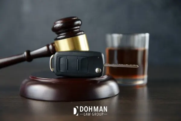 Gavel and car keys next to a glass of alcohol.