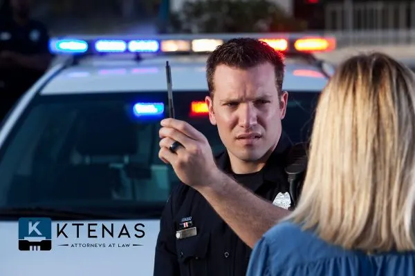 Police officer conducting a field sobriety test for a woman next to a patrol car.







