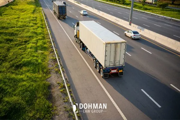 An aerial view of semi-trucks driving on a multi-lane highway with other cars.