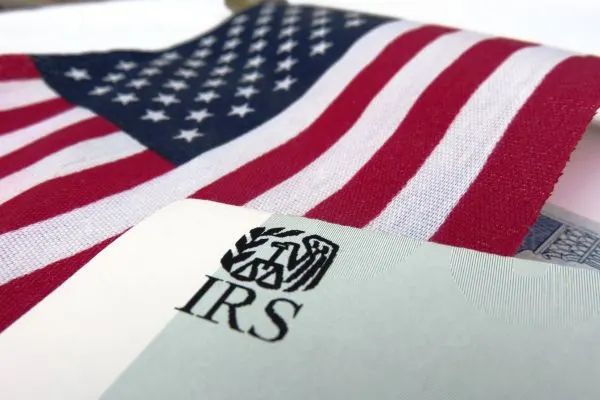A close-up of an IRS tax document positioned in front of a United States flag