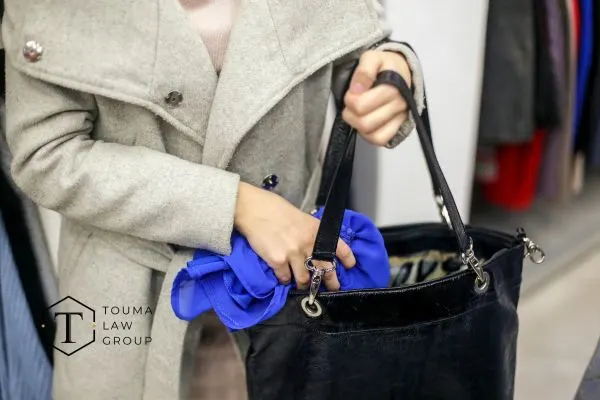 women putting a shirt in her purse implying shoplifting